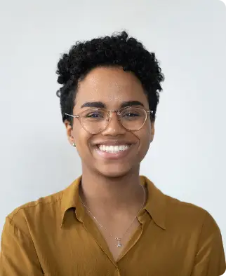 Smiling woman with glasses wearing a mustard shirt.