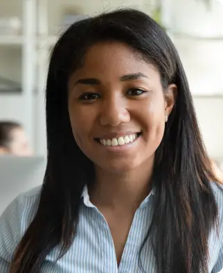 Smiling woman with long dark hair wearing a blue shirt in an office setting.