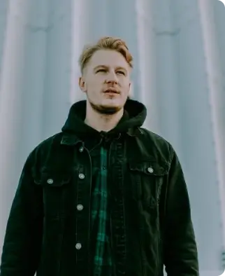 Young man wearing a black jacket standing outdoors.
